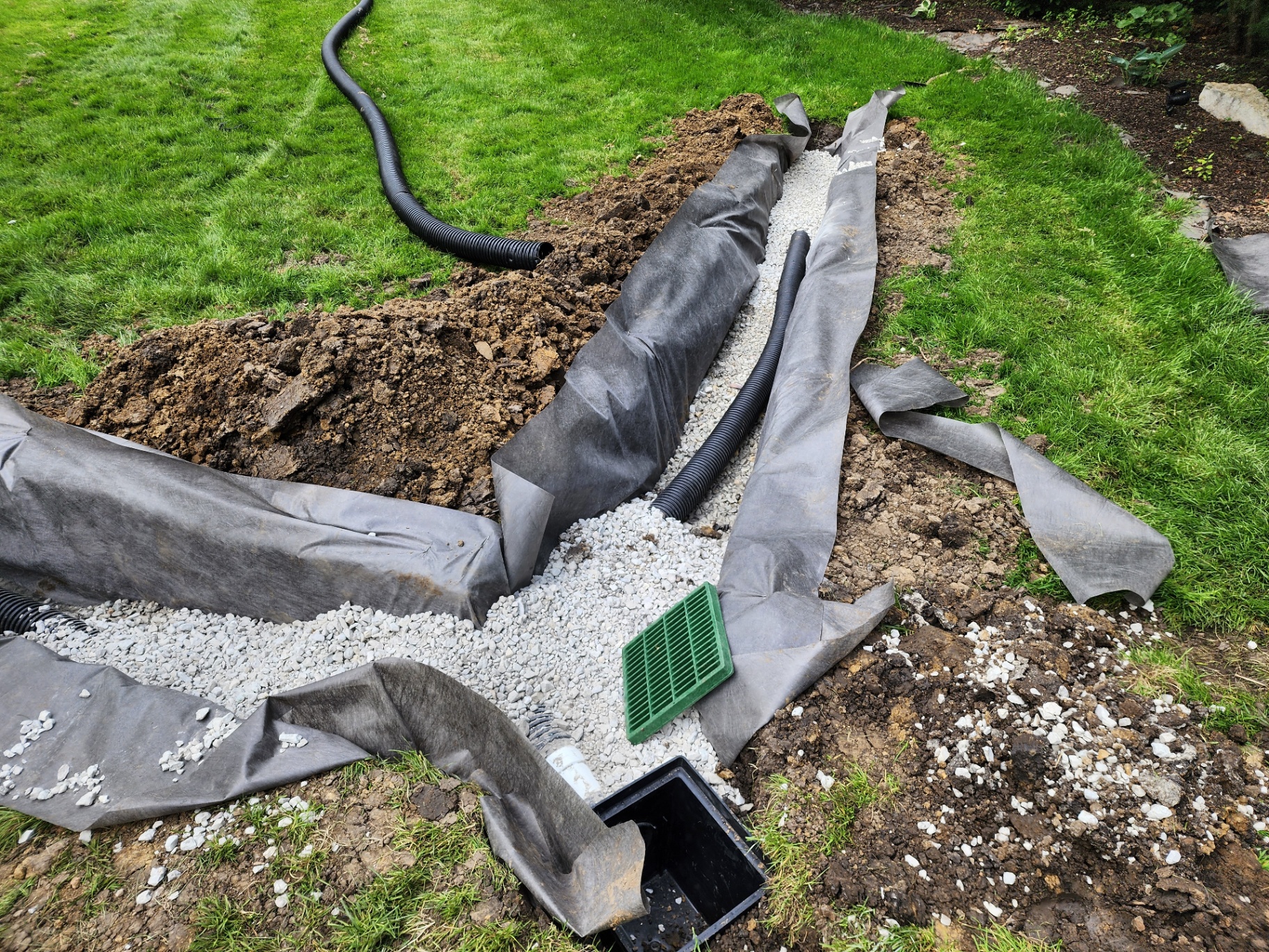 Dry well and catch basin installation with white gravel and fabric wrap