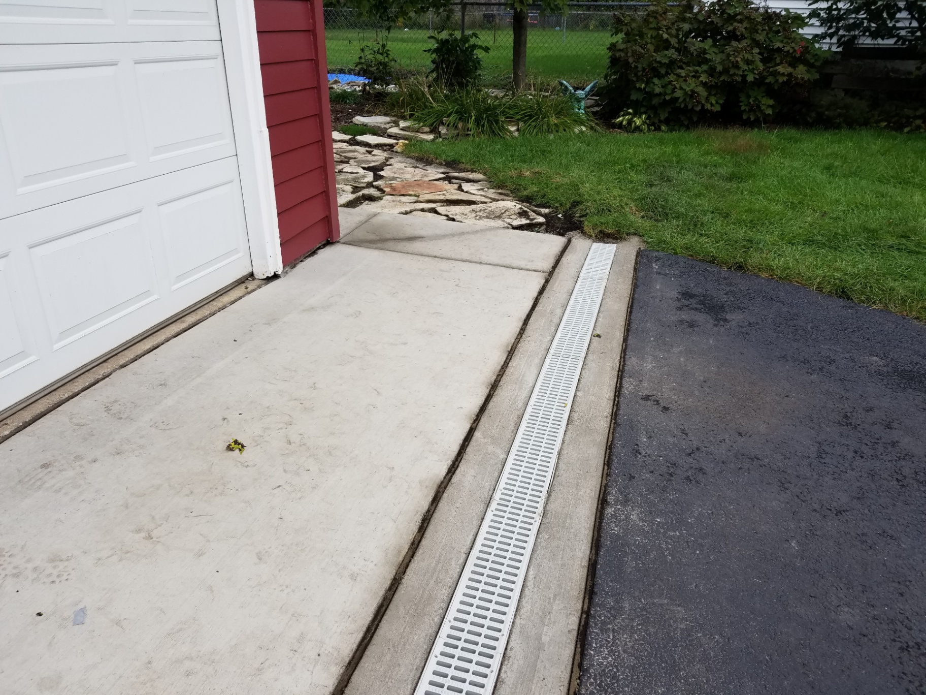 Channel drain installed between concrete driveway and asphalt apron