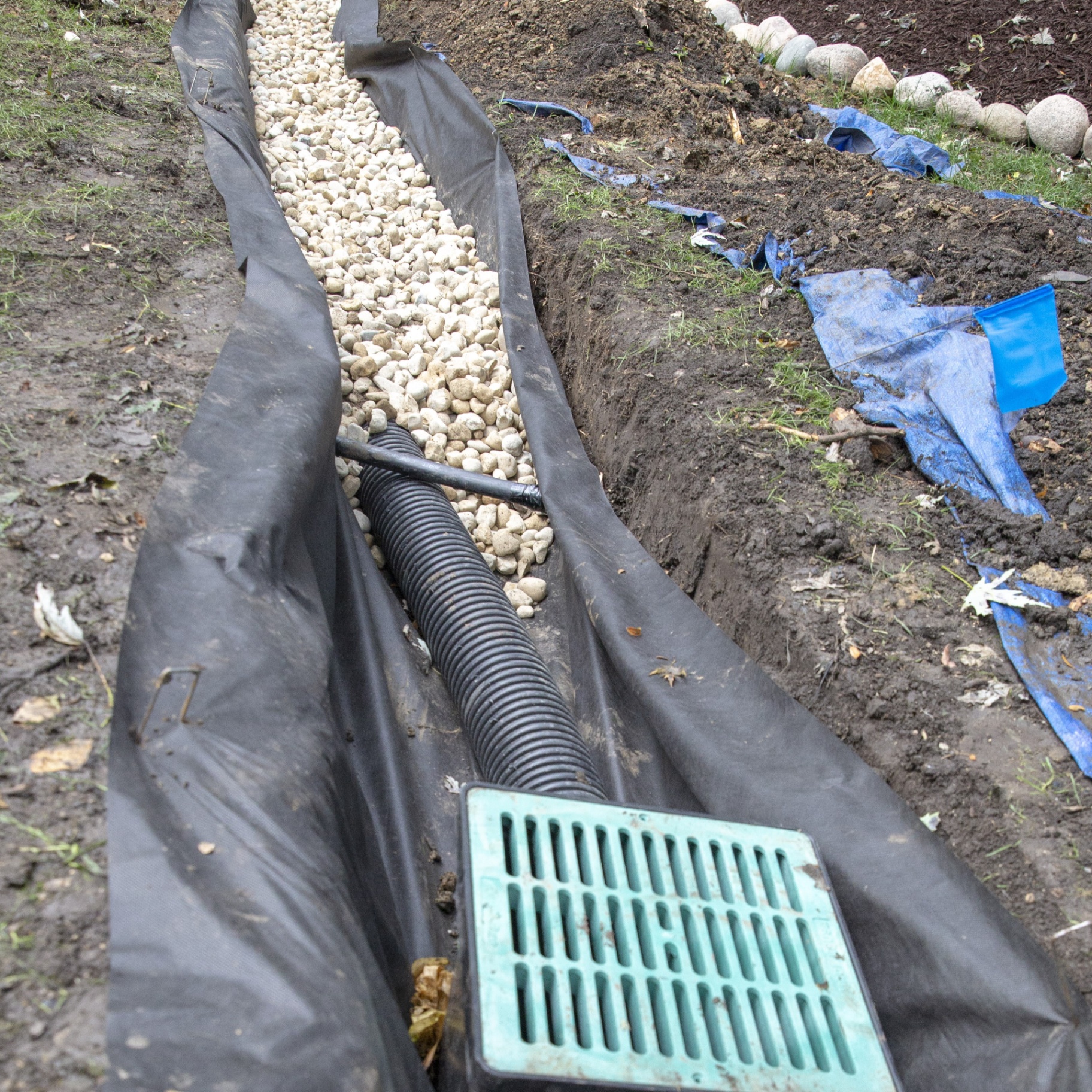 French drain trench with gravel and catch basin installed in Chicagoland lawn